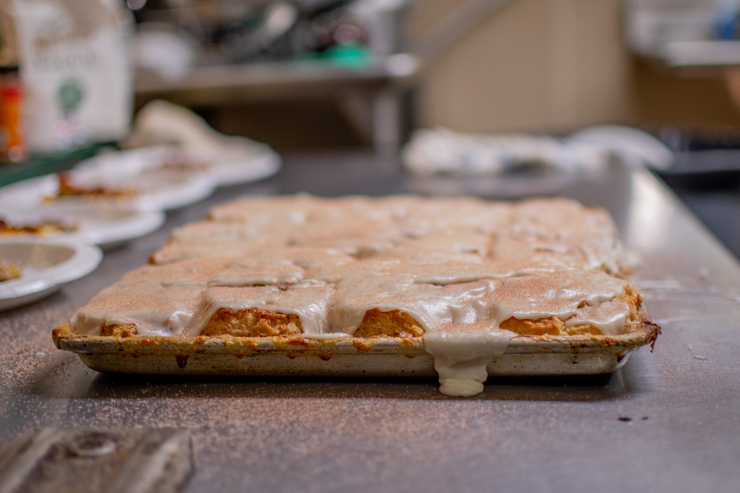 Image of freshly baked cinnamon rolls with biscuit dough, covered in icing, placed on a kitchen counter with a recipe card below.